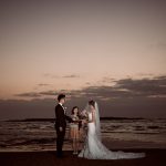 Bride and groom having a sunrise wedding ceremony on Long Reef beach